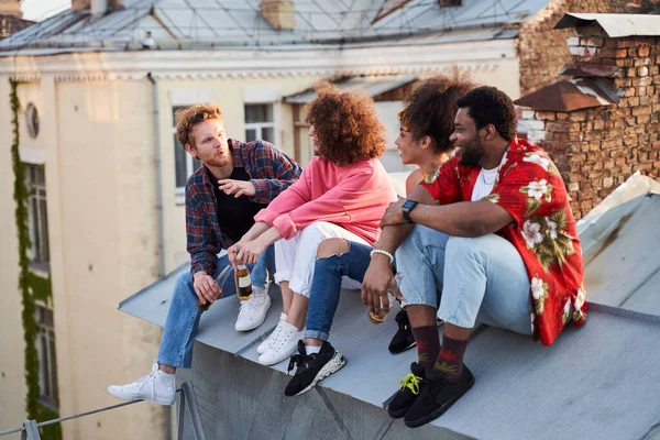 Młodzi hipsterzy z piwem rozmawiający na dachu miasta — Zdjęcie stockowe