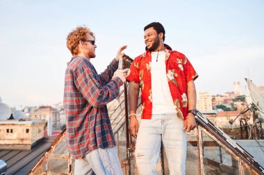 İki neşeli adam çatıda bira içiyor.