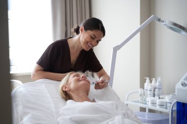 Gülümseyen güzellik uzmanı kadınlar için yaşlanmayı önleme prosedürü uyguluyor