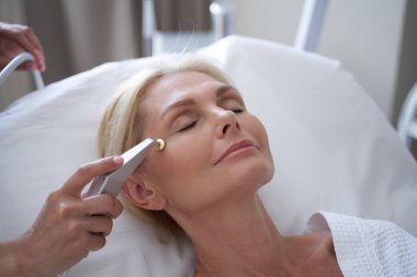 Güzeller güzeli olgun bir kadın güzellik kliniğinde kuyruklu yıldız prosedürü uyguluyor.