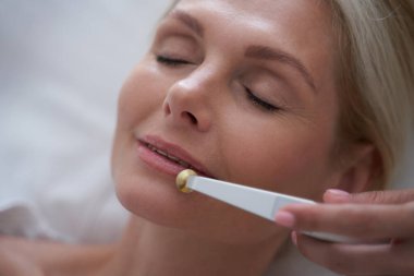 Kozmetik ameliyatları sırasında gözlerini kapatan sarışın kadın.