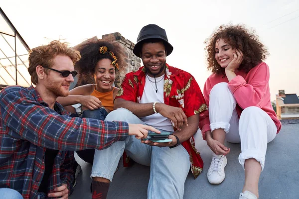 Jolly empresa joven utilizando teléfonos inteligentes juntos al aire libre — Foto de Stock