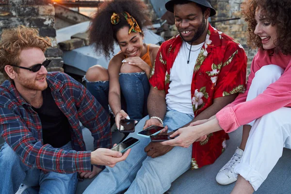 Veselí přátelé ukazující smartphony jeden druhému — Stock fotografie