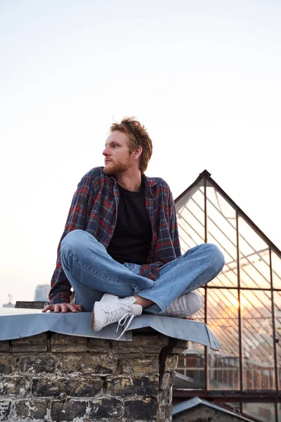 Спокійний красивий чоловік розслабляється на світанку на даху — стокове фото