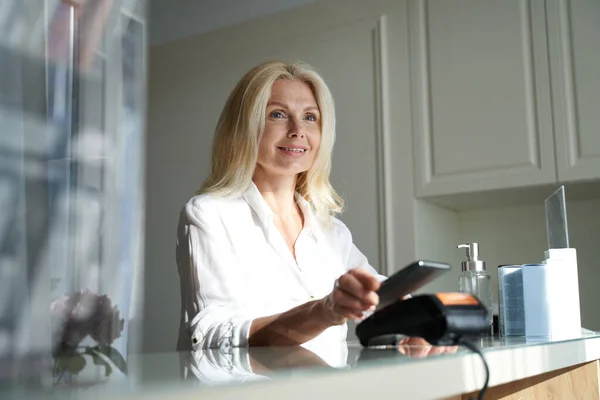 Glad söt dam håller sin smartphone nära kreditkort läsare — Stockfoto