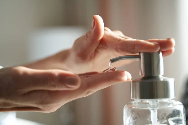 Female hands using is pumping dispenser with sanitizer