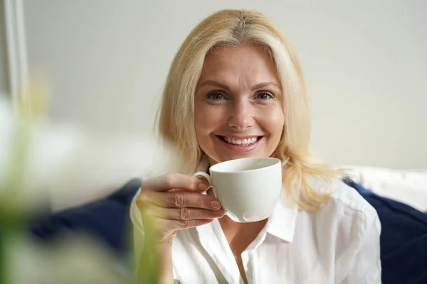 Happy pretty woman is enjoying hot drink — Stock Photo, Image