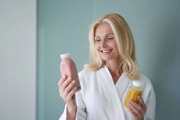健康的な飲み物の瓶を保持している笑顔大人の女性 — ストック写真