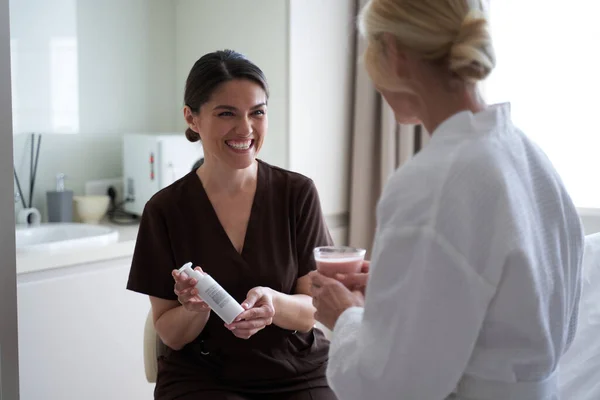 Usmívající se kosmetolog mluví s klientkou na kosmetické klinice — Stock fotografie