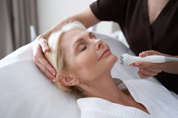 Leende dam som gör anti-aging behandlingar i skönhetskliniken — Stockfoto