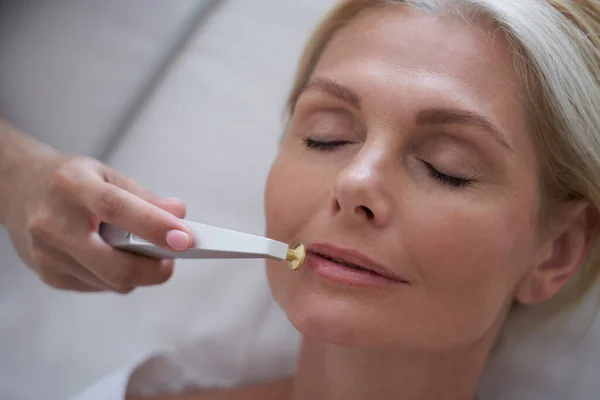 Kosmetolog med en anordning för att förbättra huden nära läpparna — Stockfoto