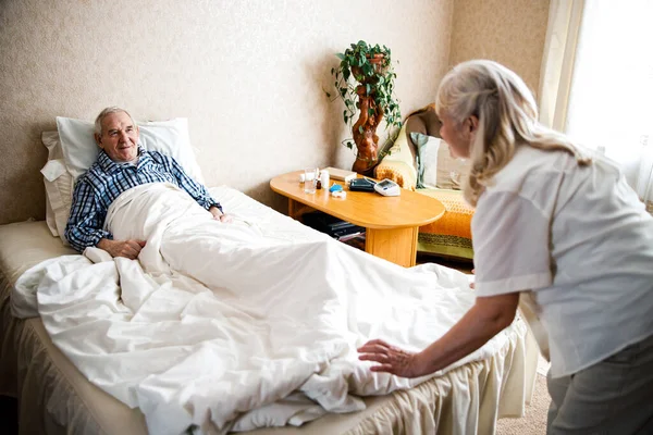 Esposa endireita seu cobertor maridos — Fotografia de Stock