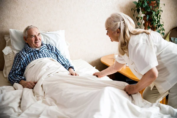 Mulher cuidadosamente ajustando cobertor para o marido — Fotografia de Stock