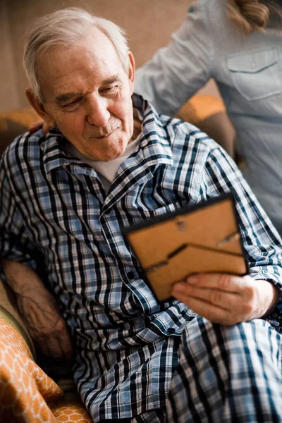 Elderly man looking at the photo in the frame — Stock Photo, Image