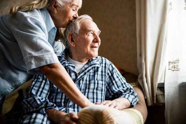 Homme souriant assis au fauteuil près de sa femme — Photo