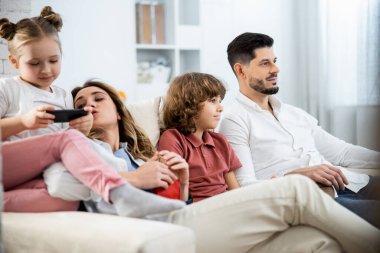 Kanepede oturan çocuklu bir aile.