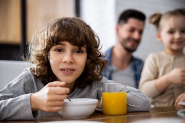 Çocuk gevrek yiyor ve portakal suyu içiyor.
