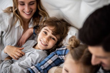 İki çocuğu battaniyenin altında mutlu bir aile.