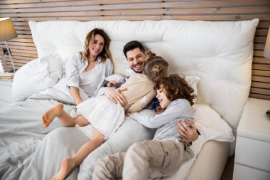 Mutlu aile yatak odasında eğleniyor.