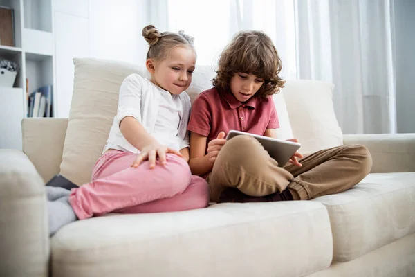 Niños jugando en la tableta digital en el sofá — Foto de Stock