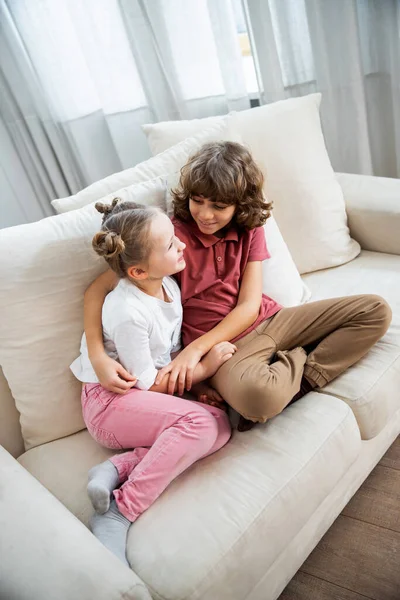 Kids siblings hug and cuddle at the sofa