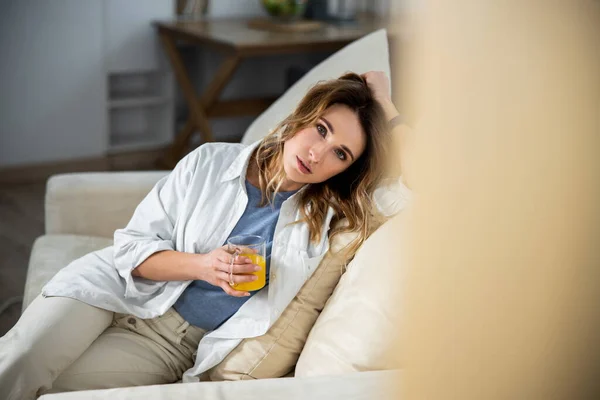 Mujer bebiendo jugo mientras está sentado en el sofá — Foto de Stock