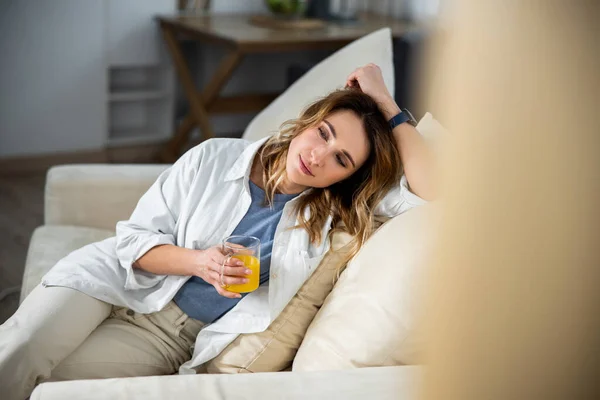 Mujer disfrutando de una bebida saludable mientras se sienta en el sofá — Foto de Stock