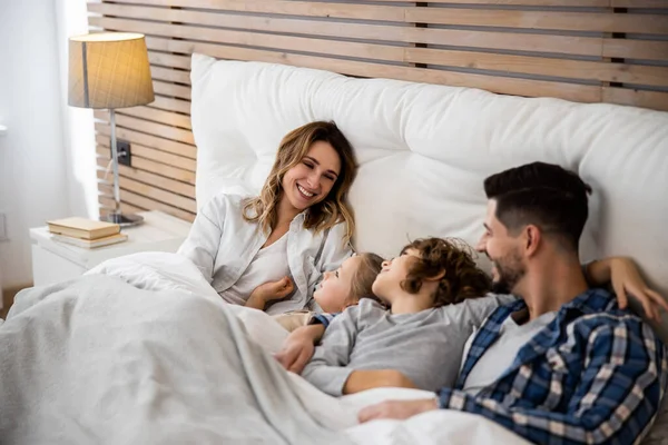 Семья разговаривает на белой кровати — стоковое фото