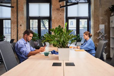 İş adamları dizüstü bilgisayarlarla masada oturuyorlar.