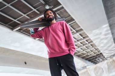 Omzunda kaykay olan bir adam.