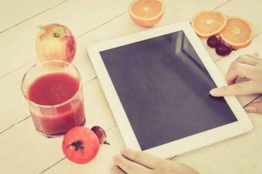 Kadın elleri boş tablet pc ve taze domates suyu ile