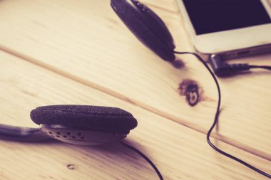ahşap arka planda cep telefonu ve kulaklık