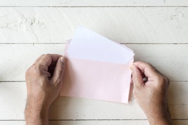 Elini tutmak bir zarf ve kağıt üzerinde ahşap arka plan