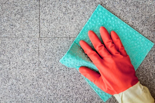 Hand and a blue cloth cleaning on a  wall