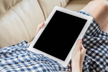 Kanepede oturan tablet bilgisayar kullanan kadın