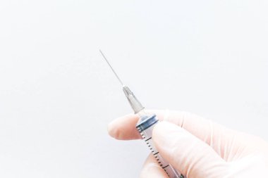 Şırınga beyaz arka plan üzerinde tutan bir lastik eldiven El