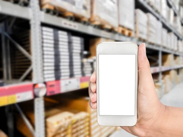 Hand holding mobile smart phone on shelf in Warehouse blurred Background