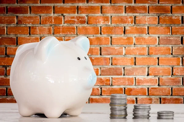 Piggy bank and coins on  brick wall background - money and saving concept