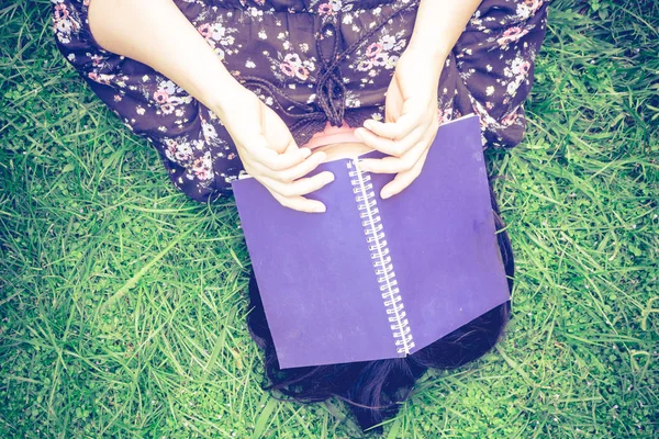 本と草の上に横たわる女性 — ストック写真