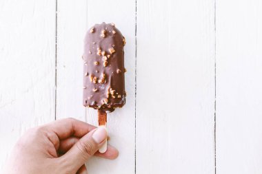 Isırık dondurma çikolatalı ahşap arka plan üzerinde tutan el