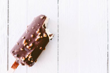 Ahşap arka plan üzerinde dondurma çikolata ısırmak