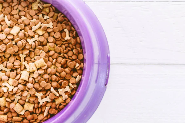 Dog food in bowl on wooden table