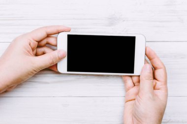 Kadın el Smartphone ahşap arka plan üzerinde tutarak