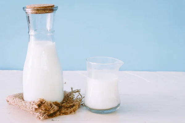 一瓶牛奶和一杯牛奶在木桌上 — 图库照片