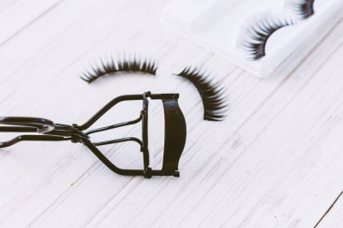 Ahşap arka plan üzerinde kıvırıcı ve yanlış eyelashes