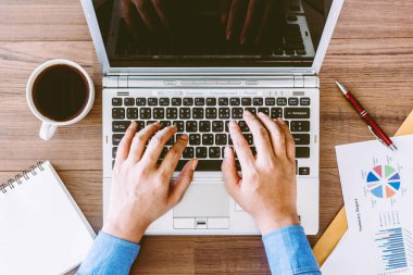 Ofiste bir masada bir dizüstü bilgisayar üzerinde çalışan iş adamı