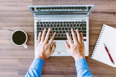 Ofiste bir masada bir dizüstü bilgisayar üzerinde çalışan iş adamı