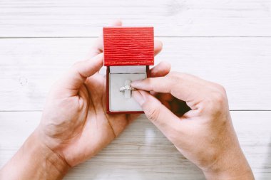 Nişan elmas yüzüğü ahşap masa üzerinde tutan el