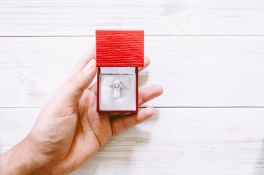 Nişan elmas yüzüğü ahşap masa üzerinde tutan el