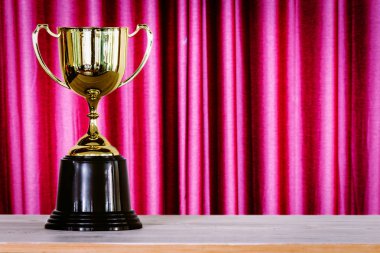 Perde arka plan önünde ahşap masa üzerinde şampiyonu altın kupa